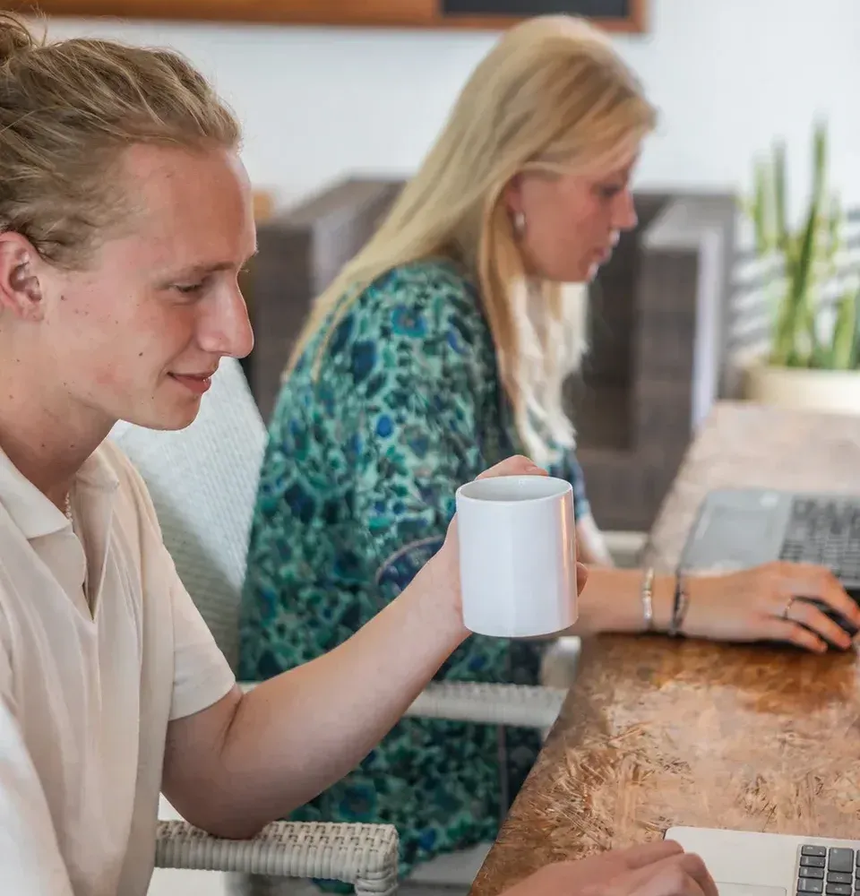 Luuk in gesprek met een collega, allebei achter hun laptop.
